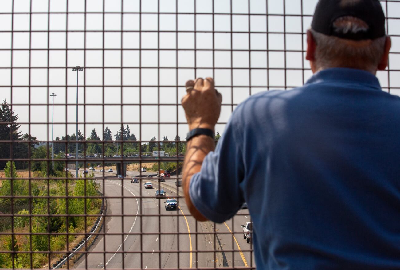 A man watches the funeral procession of fallen Clark County Sergeant Jeremy Brown from the 139th Street overpass above Interstate 5 northbound in Vancouver, Washington, on Tuesday, Aug. 3.